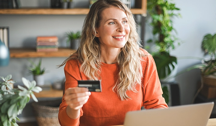 Woman holding credit card using laptop