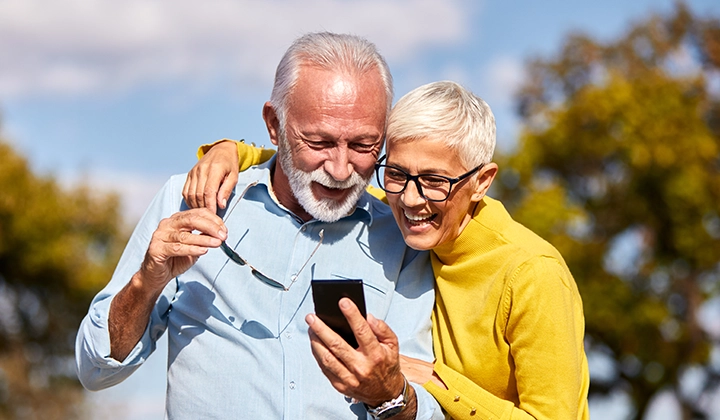 older couple outdoors looking at a mobile phone
