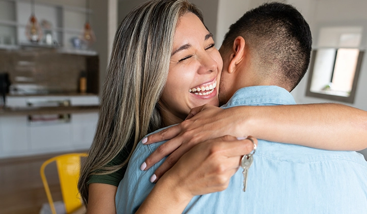 Woman hugging husband holding key to new home