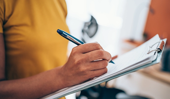 Woman holding a clip board and a pen